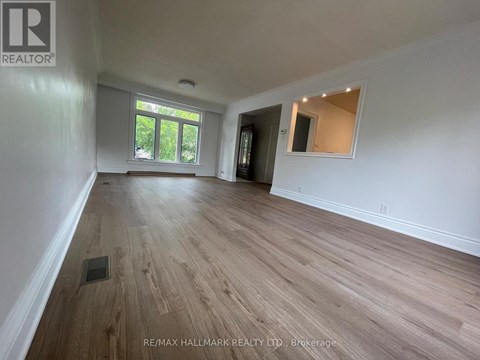 A spacious room with wooden flooring and white walls.