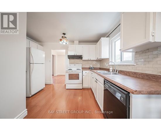 A kitchen with white appliances and wooden floors.