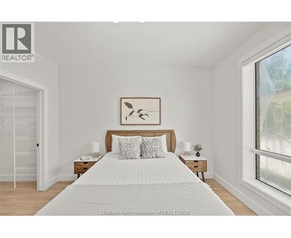 A bedroom with a large bed and a painting above it.
