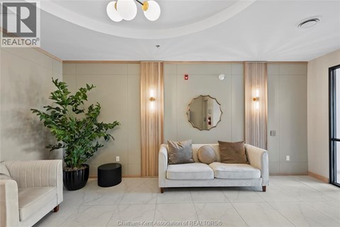 A living room with a white couch and a round mirror on the wall.