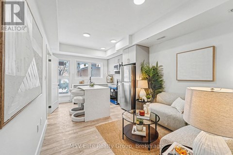 A well-lit, modern living room with a glass coffee table and a grey sofa.