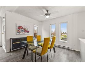 A dining room with a glass table and yellow chairs.