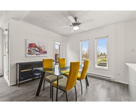 A dining room with a glass table and yellow chairs.