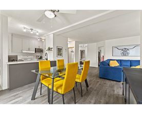 A modern kitchen with a dining table and yellow chairs.