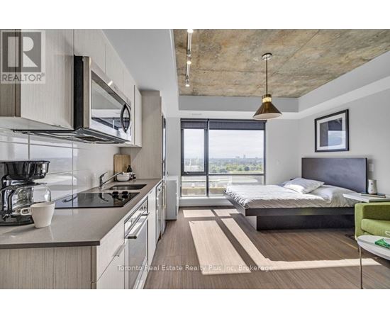 A modern kitchen with a large island and a bedroom with a large bed and a view.