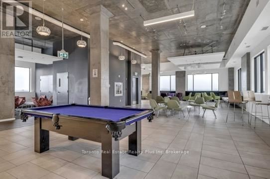 A pool table is in the middle of a room with chairs around it.