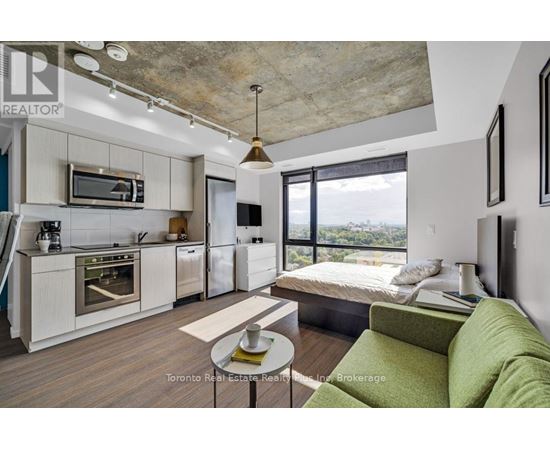 A modern kitchen with a green couch in the living room.