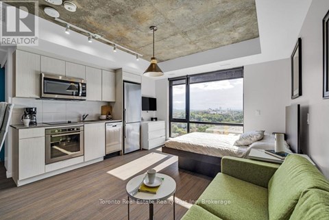 A modern kitchen with a green couch in the living room.