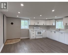 A kitchen with white cabinets and a wood floor.