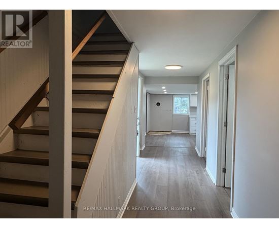 A hallway with a staircase on the left and a door on the right.