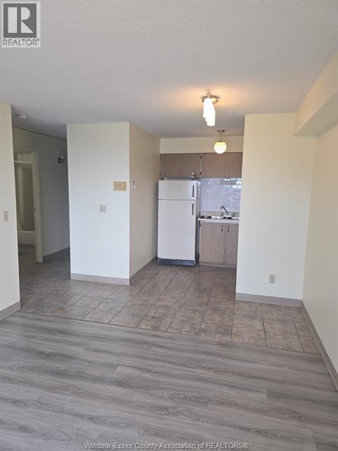 A kitchen area with a refrigerator, sink, and cabinets.