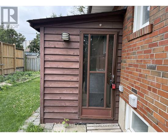 A brown wooden shed with a glass door is situated next to a brick wall.