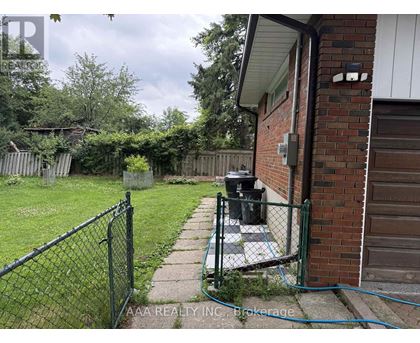 A backyard with a fence, a trash can, and a hose.