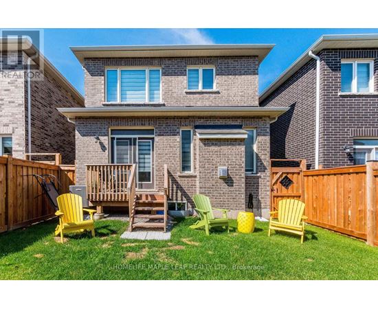 A house with a brown brick exterior and a small front yard with yellow chairs.