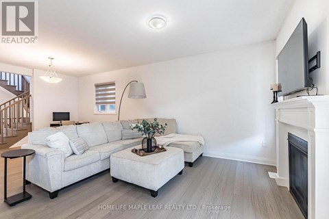 A living room with a white couch and a television on the wall.