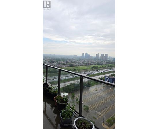 A balcony with potted plants overlooks a cityscape.