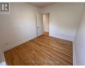 A room with wooden flooring and white walls, with a door on the right.
