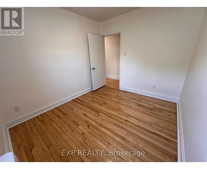 A room with wooden flooring and white walls, with a door on the right.