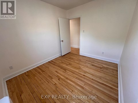 A room with wooden flooring and white walls, with a door on the right.