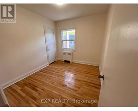 A room with wooden flooring and a window with a view of a building outside.