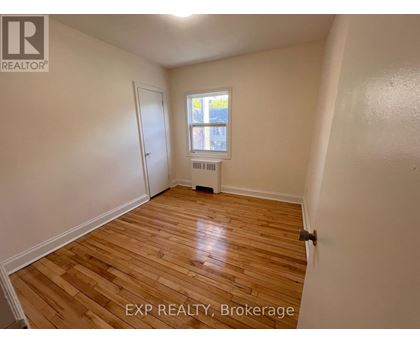 A room with wooden flooring and a window with a view of a building outside.