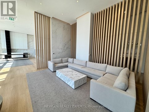 A modern living room with a grey sofa and a wooden panelled wall.