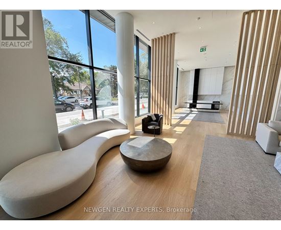 A modern waiting room with a curved white sofa and a wooden coffee table.
