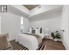 A bedroom with a bed, a chair, and a plant.