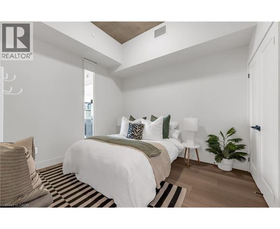 A bedroom with a bed, a chair, and a plant.