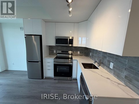 A kitchen with white cabinets and a black fridge.