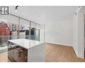 A white kitchen with a glass wall and wooden floors.