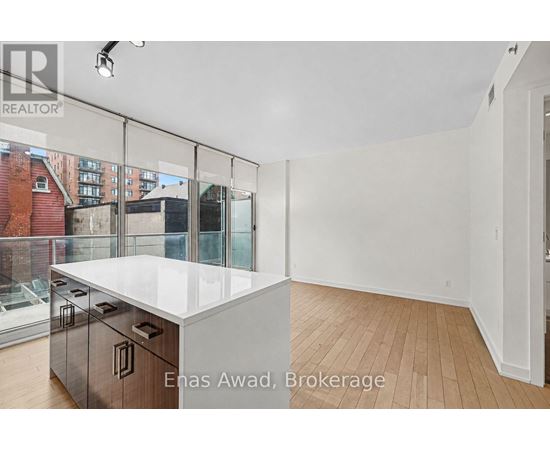 A white kitchen with a glass wall and wooden floors.