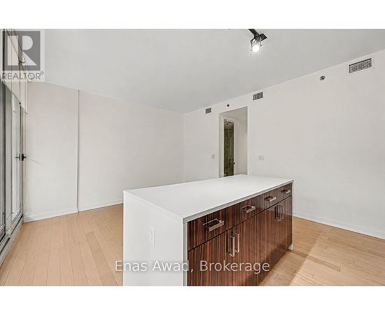 A white kitchen island with wooden drawers in a white room.