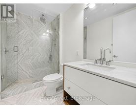A bathroom with a white toilet and a marble shower.