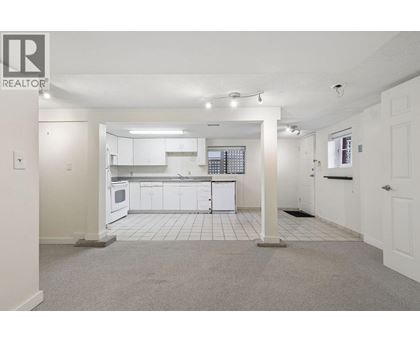 A spacious kitchen with white cabinets and appliances in a realtor listing photo.