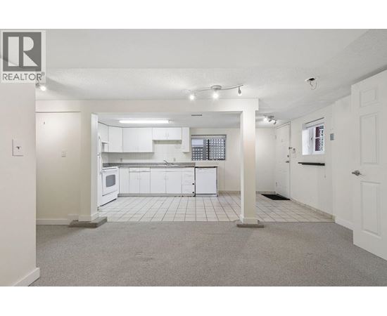 A spacious kitchen with white cabinets and appliances in a realtor listing photo.