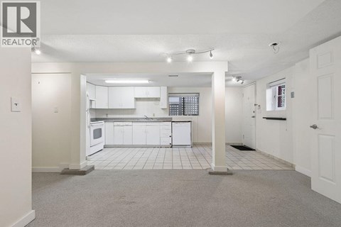 A spacious kitchen with white cabinets and appliances in a realtor listing photo.