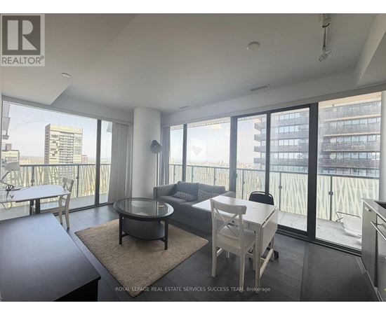 A living room with a glass table and chairs, a sofa, and a view of the city.