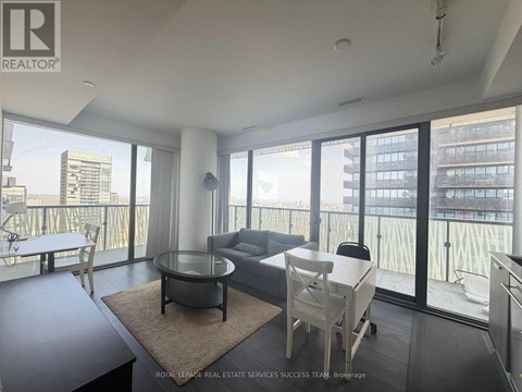 A living room with a glass table and chairs, a sofa, and a view of the city.