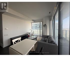 A modern living room with a glass table and grey couch.