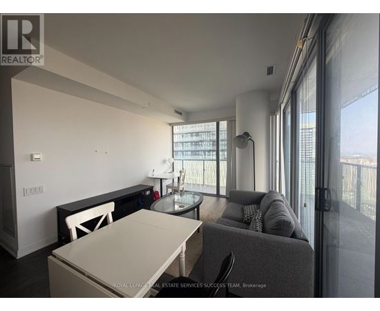 A modern living room with a glass table and grey couch.