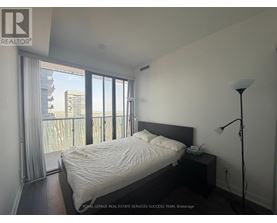 A bedroom with a large bed and a balcony overlooking a cityscape.