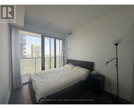 A bedroom with a large bed and a balcony overlooking a cityscape.