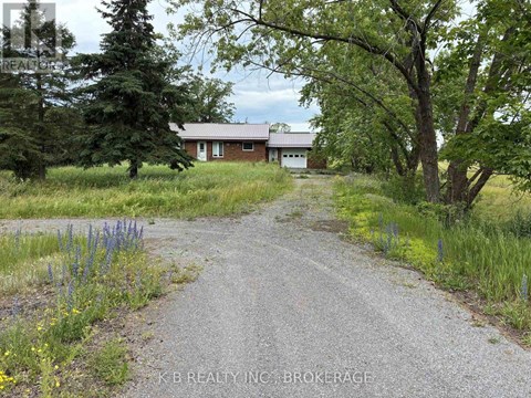 A gravel road leads to a house in the countryside.