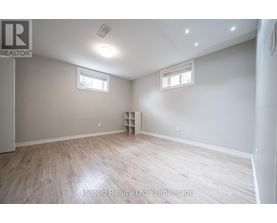 A room with wooden flooring and two windows.