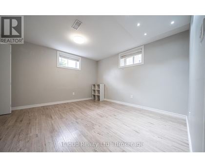 A room with wooden flooring and two windows.