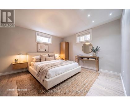 A bedroom with a large bed, a nightstand with a lamp, and a small table with a plant on it.