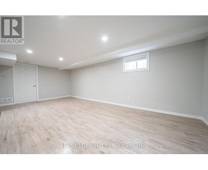 A spacious room with wooden flooring and a window.