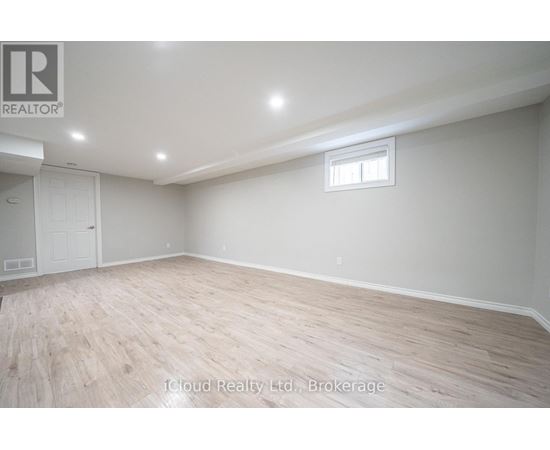 A spacious room with wooden flooring and a window.