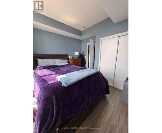 A bedroom with a purple bedspread and a wooden bed.